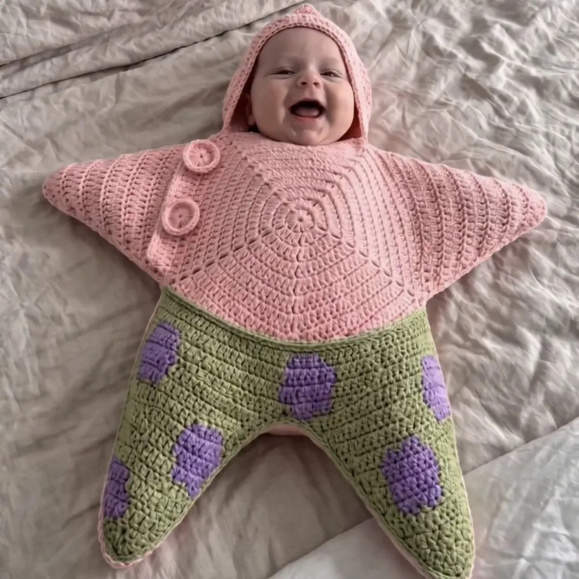Baby wearing a pink and green star-shaped hooded outfit